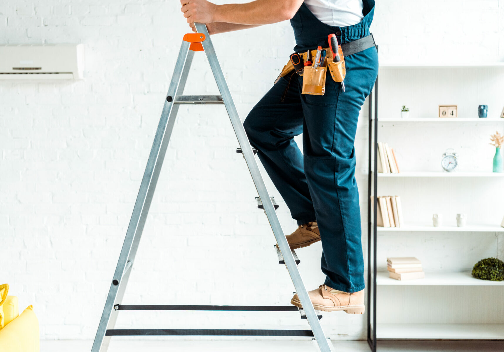 cropped view of installer in overalls climbing ladder